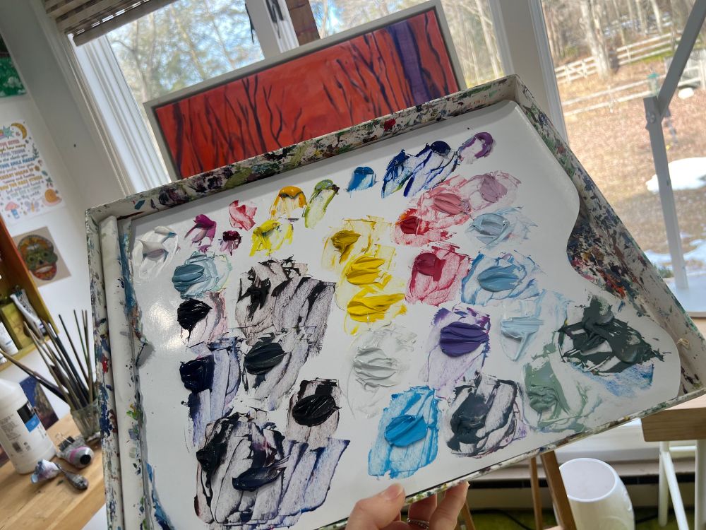 Picture of a colorful artist’s palate with dark neutrals and bright pinks purples yellows and blues for a sunset forest scene