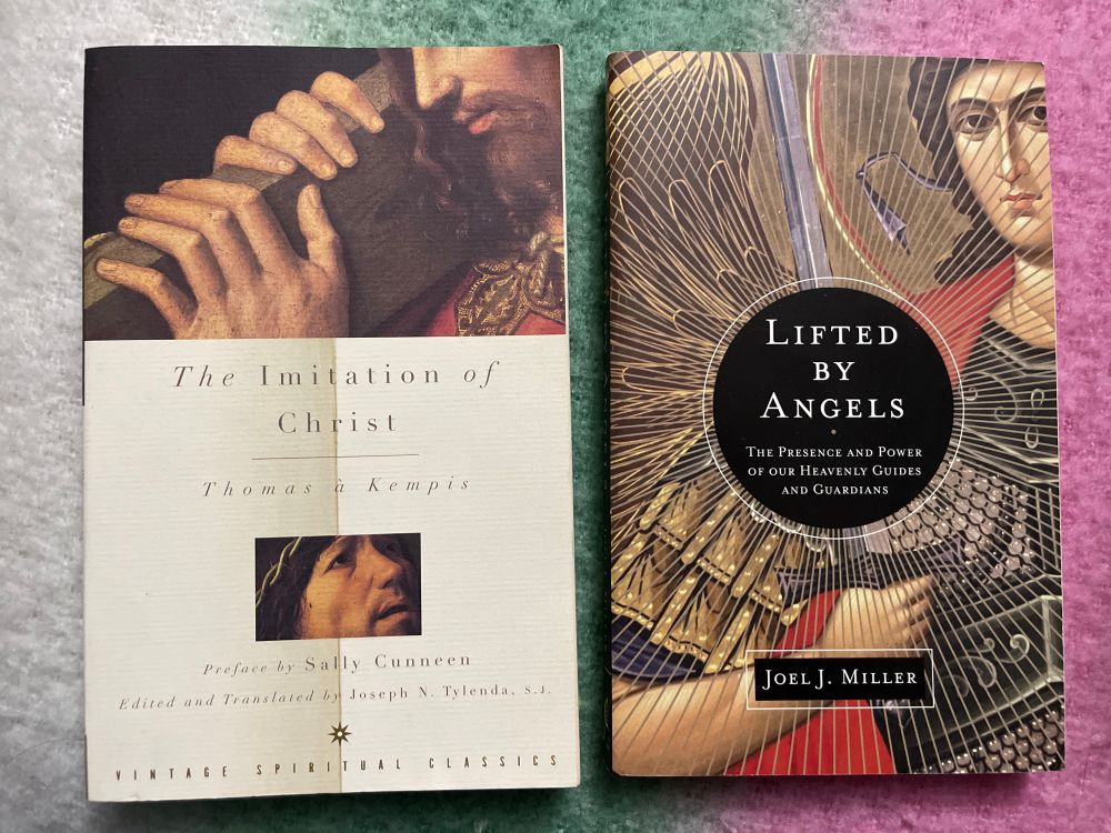 Two books lying side by side on a green and pink gradient background.
	•	Left book: The Imitation of Christ by Thomas à Kempis, Vintage Spiritual Classics edition, featuring a cover with a painting of Christ carrying the cross.
	•	Right book: Lifted by Angels: The Presence and Power of Our Heavenly Guides and Guardians by Joel J. Miller, with a cover design of golden angel wings and rays radiating from a central circle.