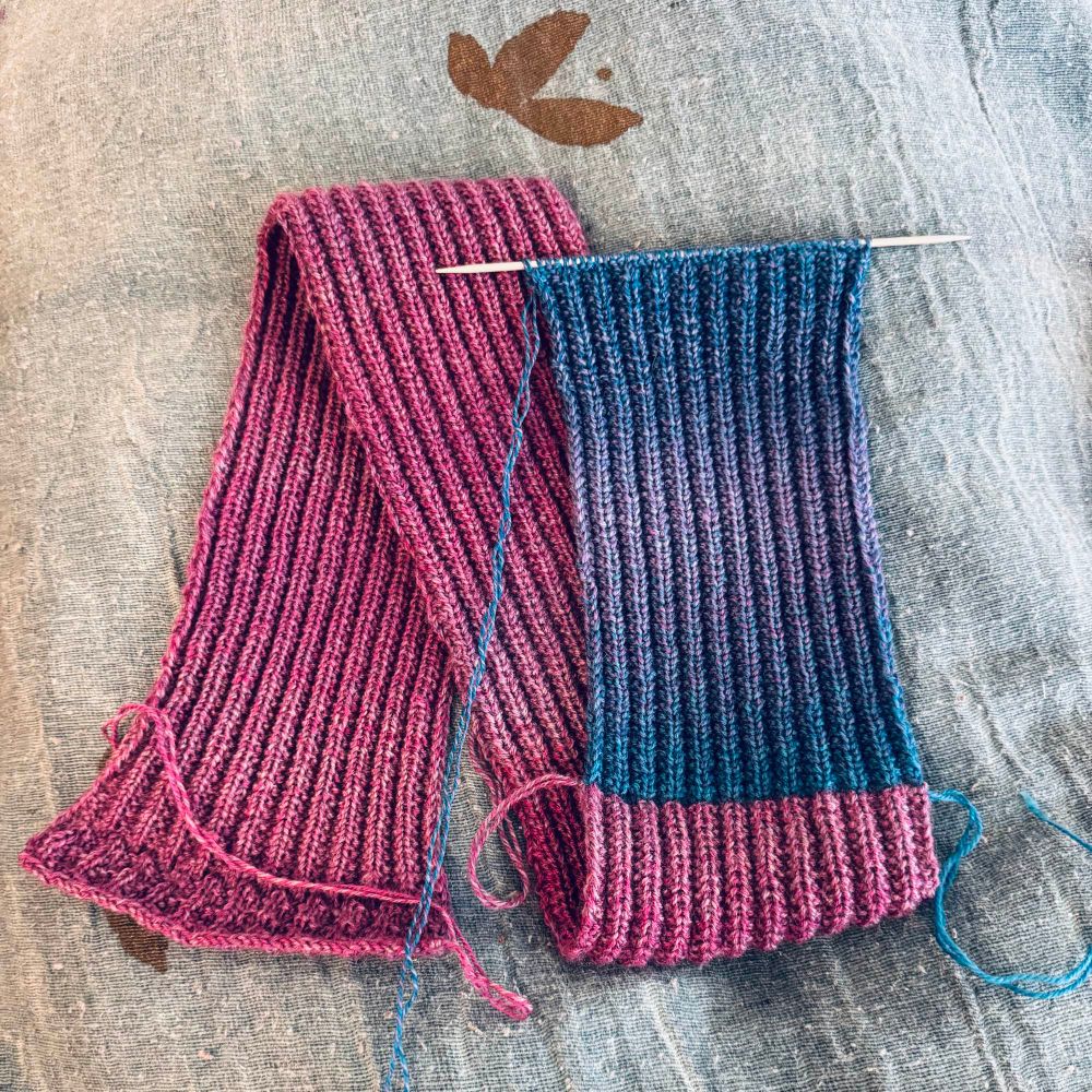 A rib knitted scarf with pink, blue and purple gradient yarn. 
