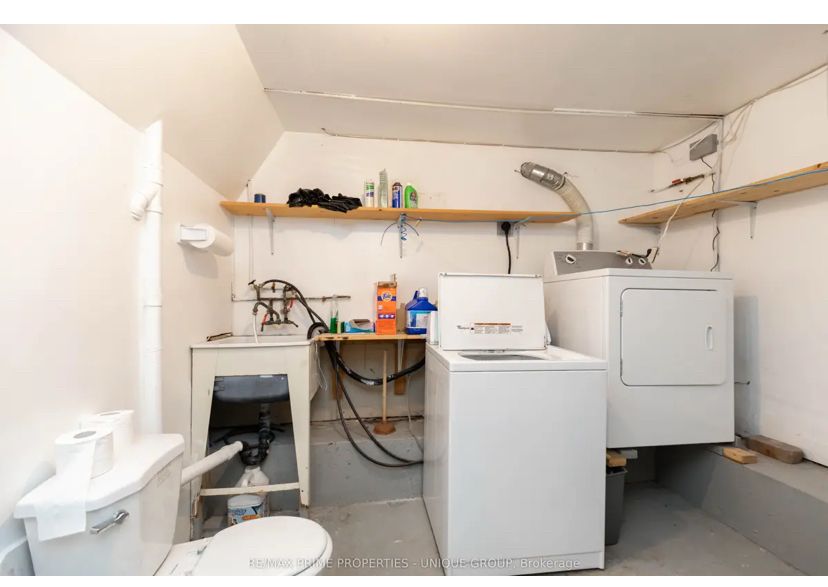 laundry room with a toilet. the dryer is next to the washing machine but has been placed about 2 feet higher and precariously sits on two wooden rails
