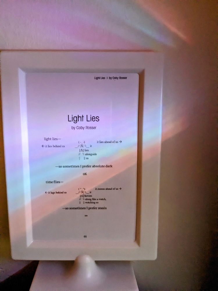 Framed poem, "Light Lies" by Coby Rosser. From Apparition Lit issue 27. Prismatic light shines across the surface of the frame. Available to read at Apparition Lit. Poem includes an astronaut/spaceman character that resembles ascii art. First part reads:

"Light lies/It lies ahead of us/It lies behind us/It lies/lies alongside us/--so sometimes I prefer absolute dark/0k

Time flies/it zooms ahead of us/it lags behind us/it havers along like a watch, watching us/--so sometimes I prefer stasis/∞"