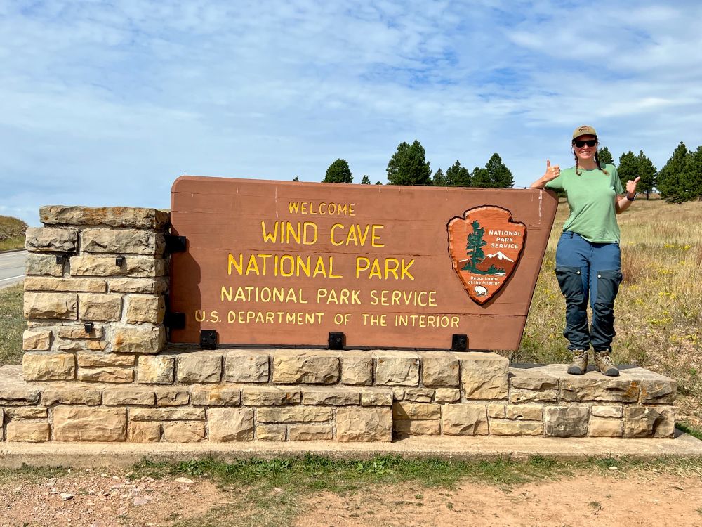 Me doing a double thumbs up by the Wind Cave NP sign
