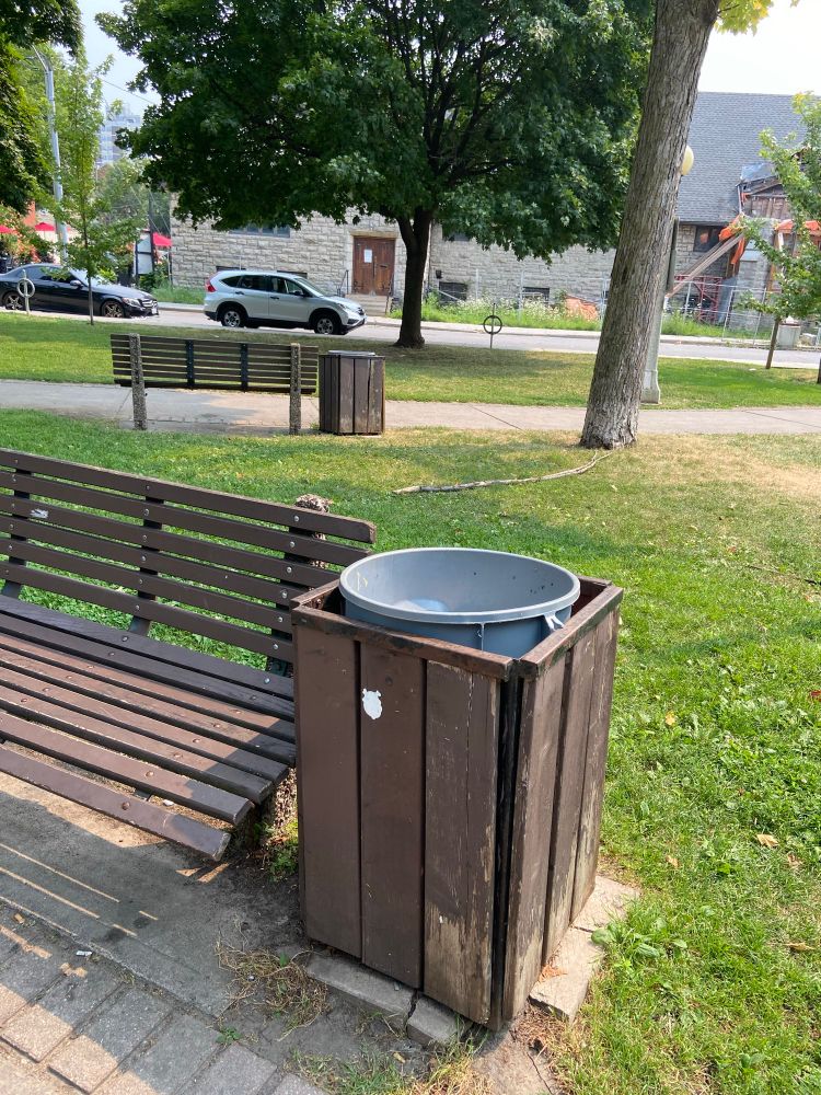 A wood frame garbage receptacle with a rubber bin placed inside