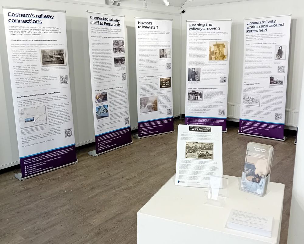 5 pull-up banners in front of white walls, on a wooden floor. Leaflets on a stand in front.