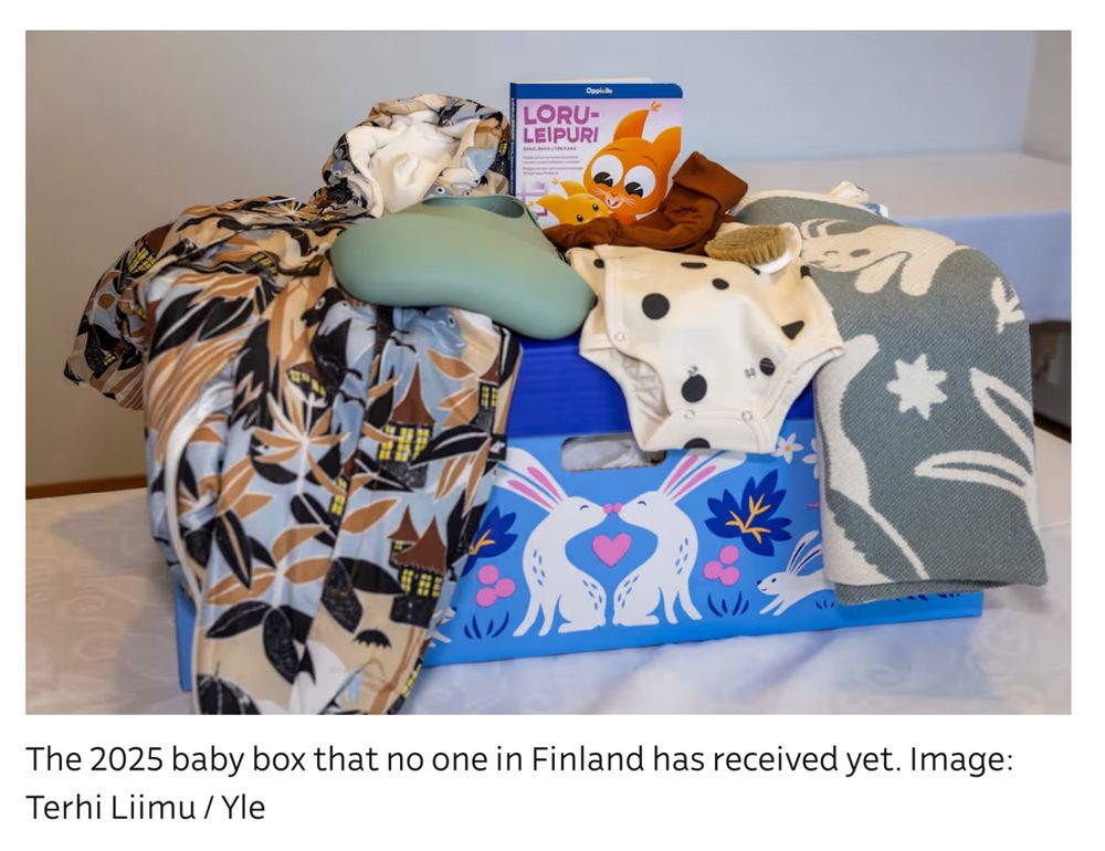 A photo of a Finnish baby box, with several items visible, including a bib, towel, and a winter overall. Underneath there is the text: 

The 2025 baby box that no one in Finland has received yet. Image: Terhi Liimu / Yle