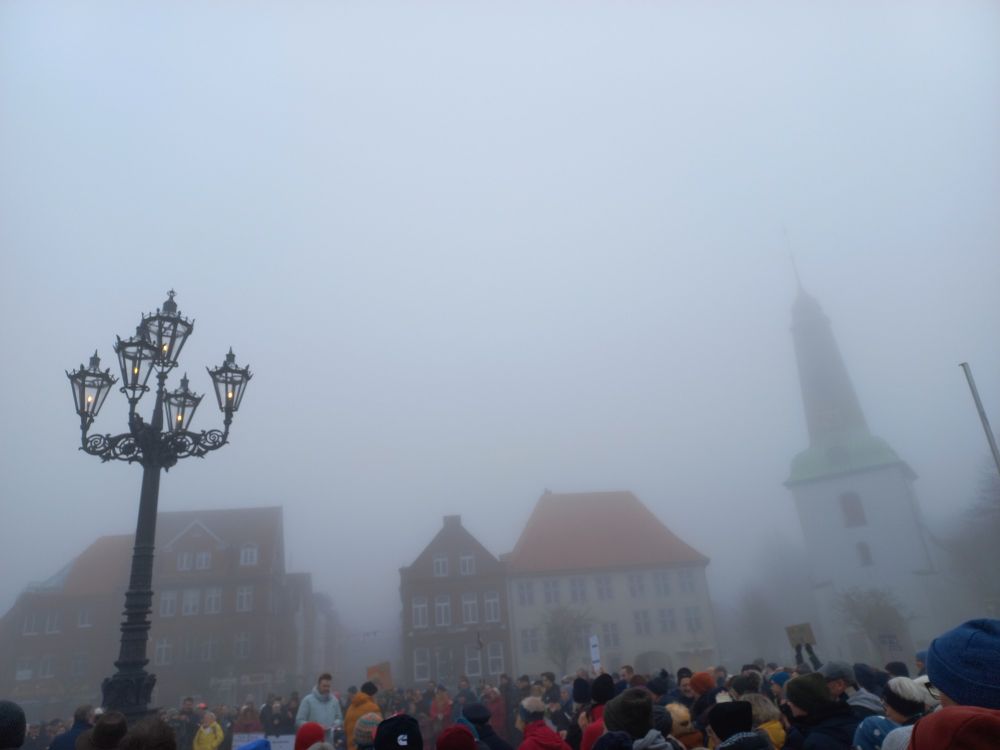 Menschenkette zum Schutz der Demokratie in Glückstadt, im Hintergrund zentraler Straßenleuchter auf dem Marktplatz und Kirche