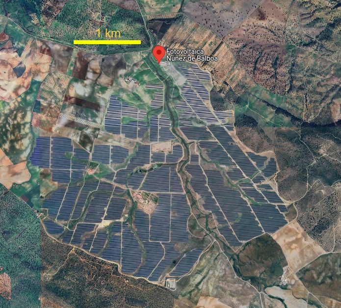 Imagen de googlemaps de la planta fotovoltaica de Nuez de Balboa con la cartografía fotográfica de la aplicación. Un punto de marcador rojo indica el nombre de la megaplanta. Una línea amarilla horizontal sobre la que está escrito "1 km" da la escala.