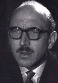Lionel Jeffries in The Quatermass Experiment. A balding man with a moustache and glasses, looking about 50.