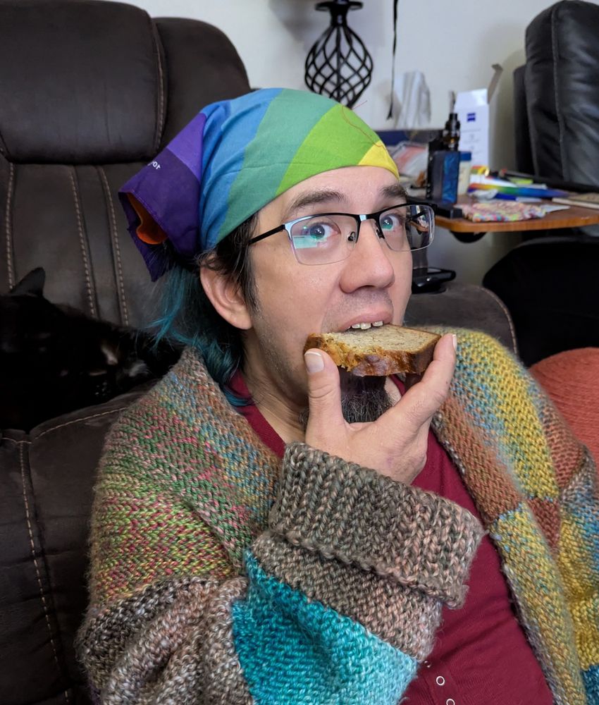 A colorfully dressed bloke snacking on what looks to be a mighty fine piece of banana bread.