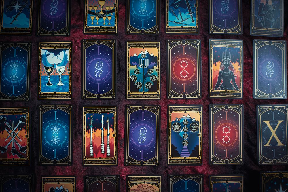A picture of the Decuma deck from Golden Lasso Games surrounded by the tarot-inspired cards that make up the deck.