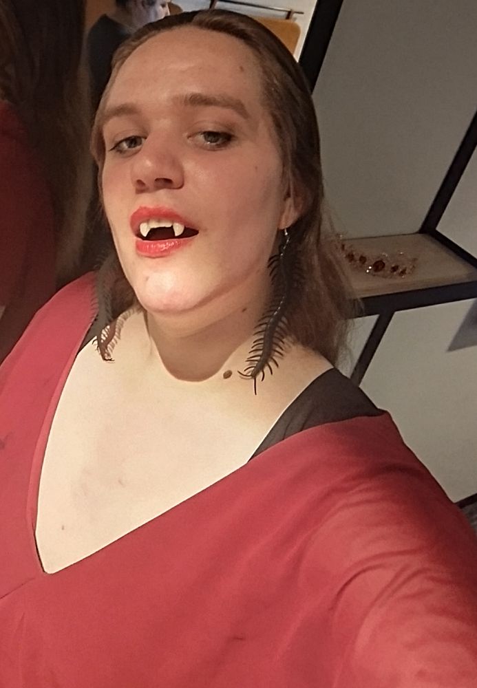 Ivy, with vampire fangs, caterpillar earrings and a red dress