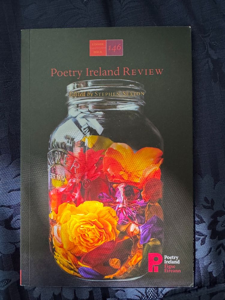 Image of a copy of Poetry Ireland Review issue 146 Edited by Stephen Sexton with a jar full of bright colored flowers. 