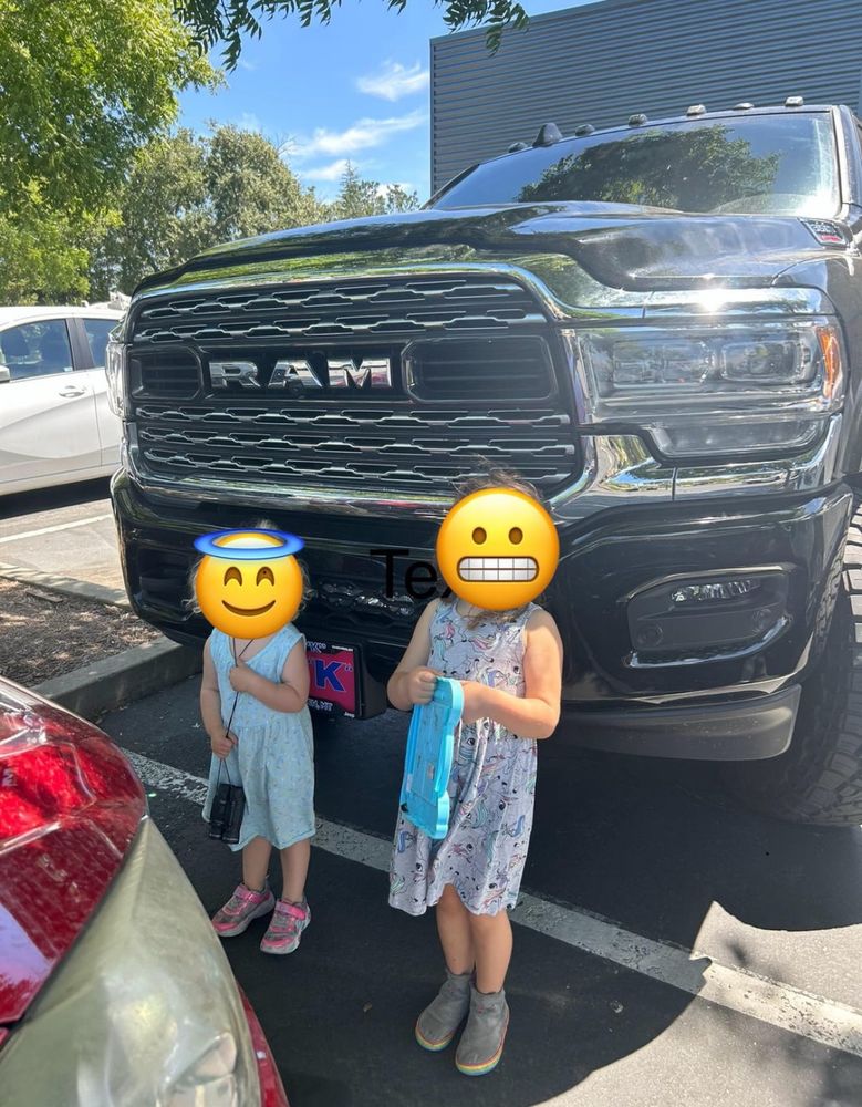 Two children stand in front of dodge ram pickup truck with a very high front hood height. One child does not even come up to the bottom of the truck’s large front grill, while the other just barely clears the bottom of that grill.  (Is grill the right word? I don’t know anything about truck parts) 

It would be absolutely impossible to see those children from the front windshield.  