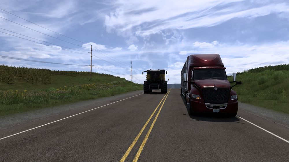A picture from within American Truck Simulator (ATS) of my truck and trailer passing a slow moving Harvester.