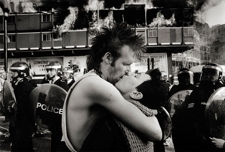 A couple kiss during the poll tax riots in 1990. they are surrounded by riot police.