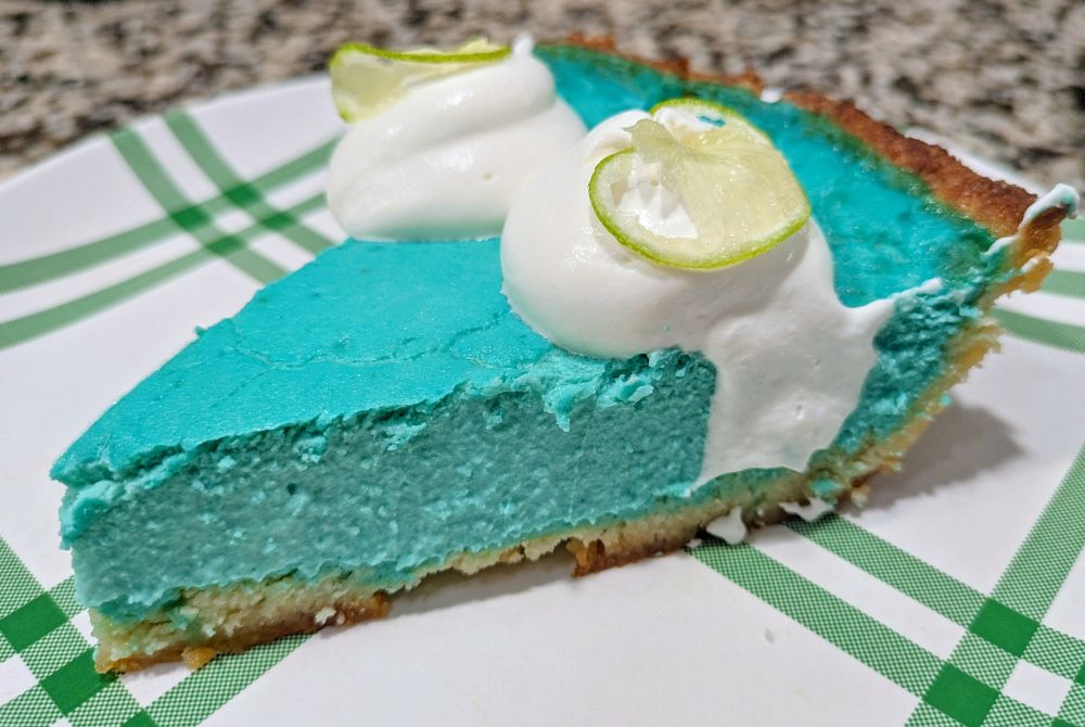 a slice of blue pie with whipped cream and thinly sliced key limes on top