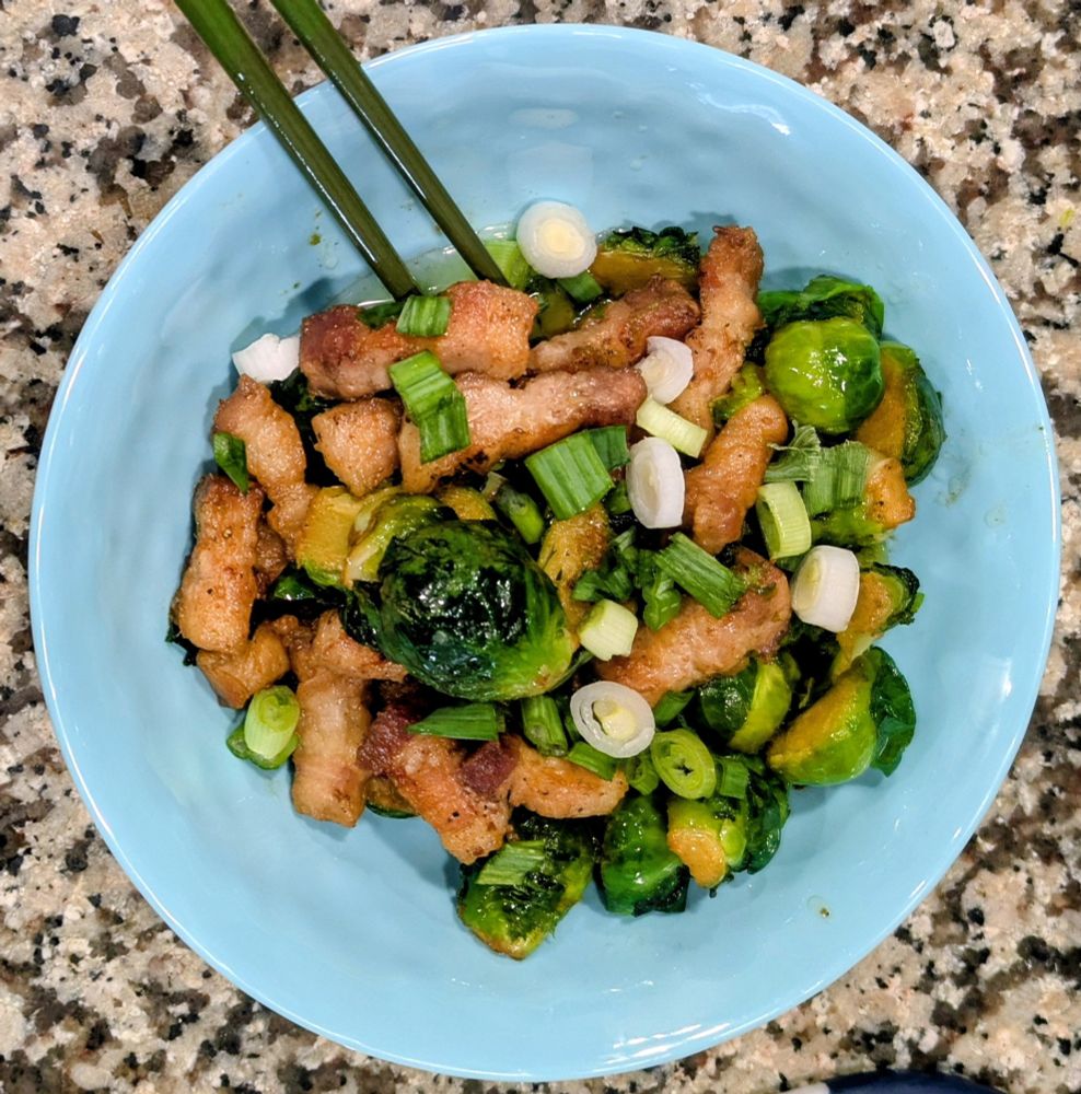 a bowl of Brussels sprouts, crisped pork belly, and green onions