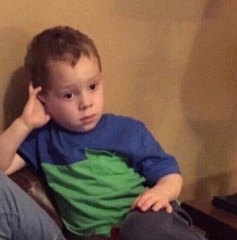 kid sitting holding their head up with their hand, distantly staring into nothing with a blank face