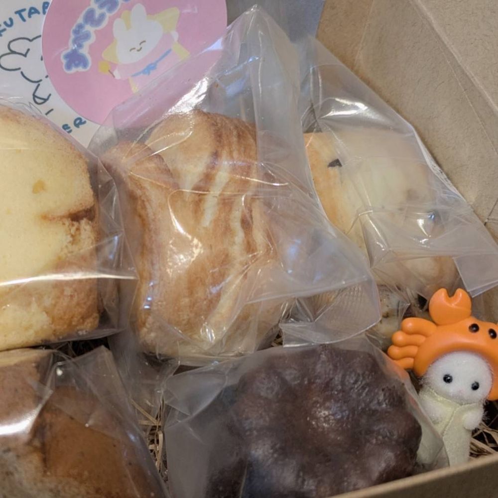 ひかり焼菓子店さんアベカワさんセレクト焼菓子ボックスのカヌレの横にお邪魔して記念撮影するシルバニアファミリーカニのあかちゃん（スコーン、シフォン、かわいいステッカーも写っている）