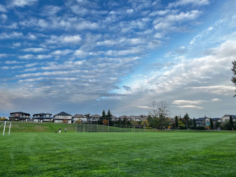 Irl photo of a soccer/baseball field with a blue sky. There’s streaks of clouds decorating it.