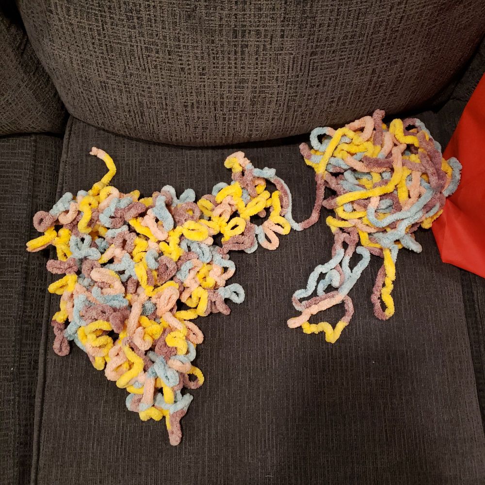 The Off The Hook yarn on a grey couch. The left is the yarn in a pile as it comes and the right is the yarn straightened