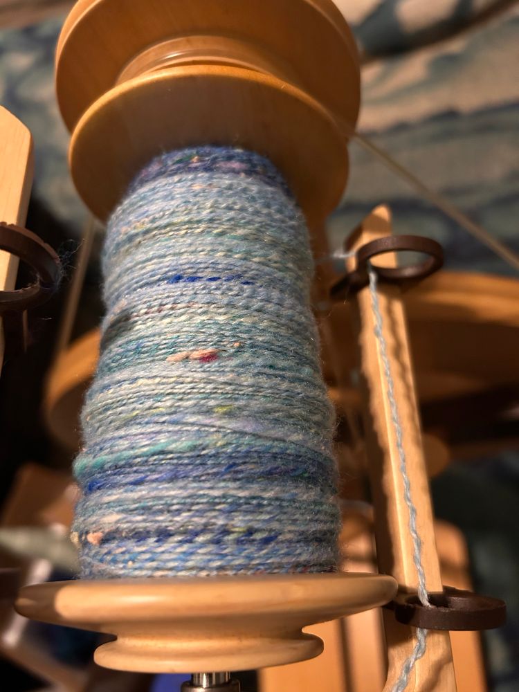 A bobbin full of plied yarn in different blues