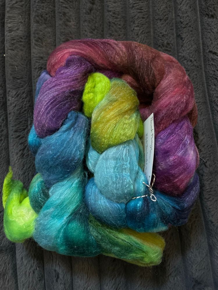Coiled braid of unspun fiber in greens, blues, reds, and purples. 