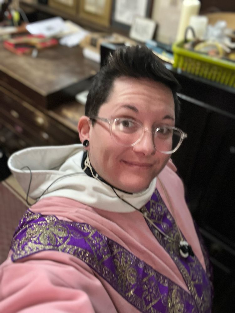 A priest wearing rose vestments smiling 