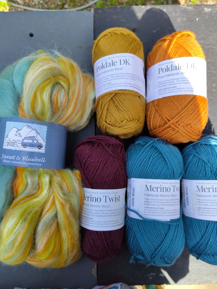 Balls of yarn in mustard, spice, teal & aubergine colours. Spinning fibre in turquoise and yellow 