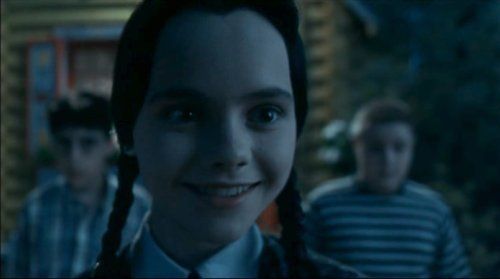 Christina Ricci as Wednesday Addams smiling reluctantly in ADDAMS FAMILY VALUES