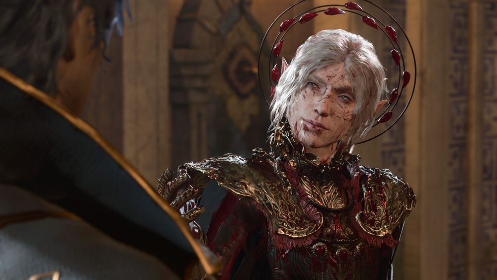 An in-game screenshot of my durge Amarie talking to Gortash. She is near the center of the frame while Gortash is to the far left of the frame; his face is obscured while her face is fully in the frame. She is a high elf with a pallid skintone and bone white hair done up in a messy crown braid, and attached to the back of her hair is a hairpiece resembling the symbol of Bhaal. She is wearing red, black, and gold armor and is covered in blood. 