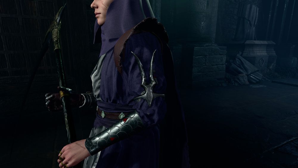 An in-game screenshot of my durge Amarie wearing her postgame armor as a cleric of Jergal. On her left arm, she is wearing a large metal decoration; this decoration is one that is used in-game as an alternate symbol of Jergal, as he is shown to be wearing it and his skeleton followers are also shown to be wearing it.