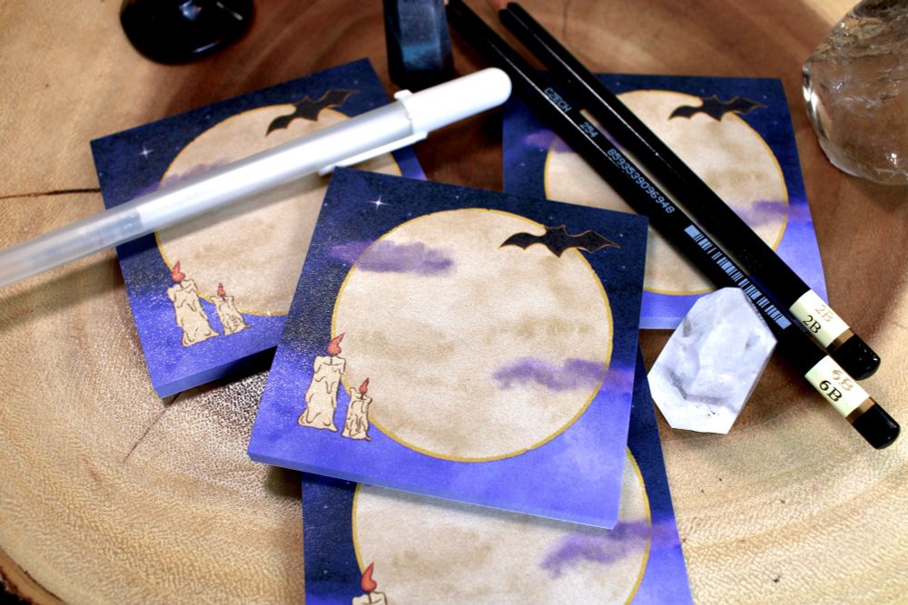 Sticky notepads featuring the moon, melting taper candles, a bat, and clouds