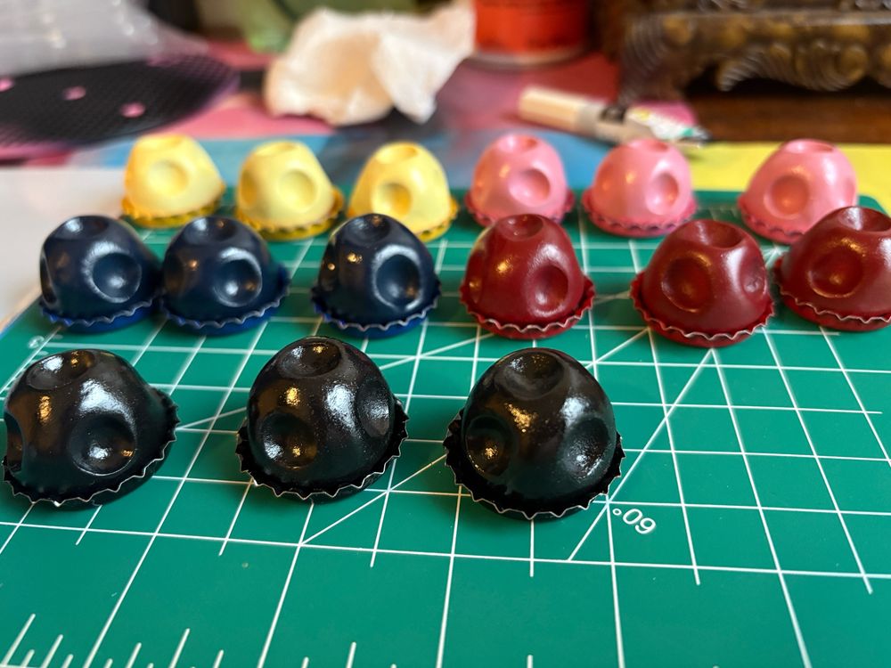 Clay mushrooms sitting inside matching colored bottle caps 