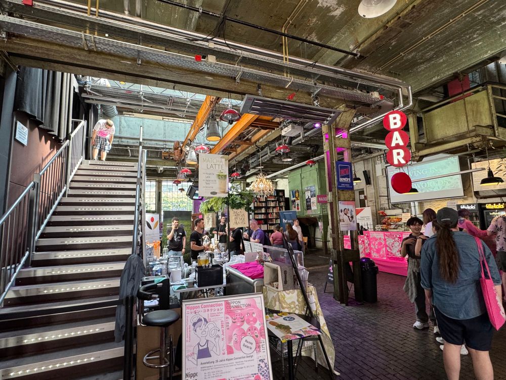Event space of Nippon Connection. Staircase on the left. Next to stairs on ground floor is a cafe and bar. Books in the far-right corner. 