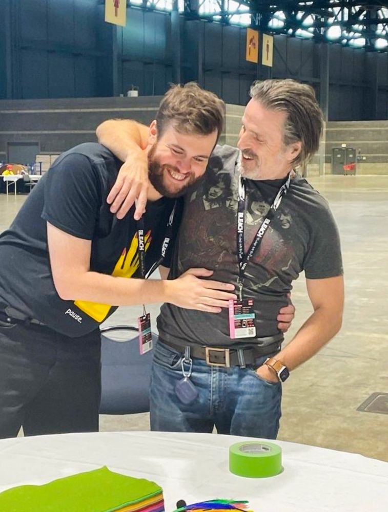 Nathan Foad and Con O'Neill together. Con has an arm around Nathan's shoulders and Nathan his hands around Con's waist