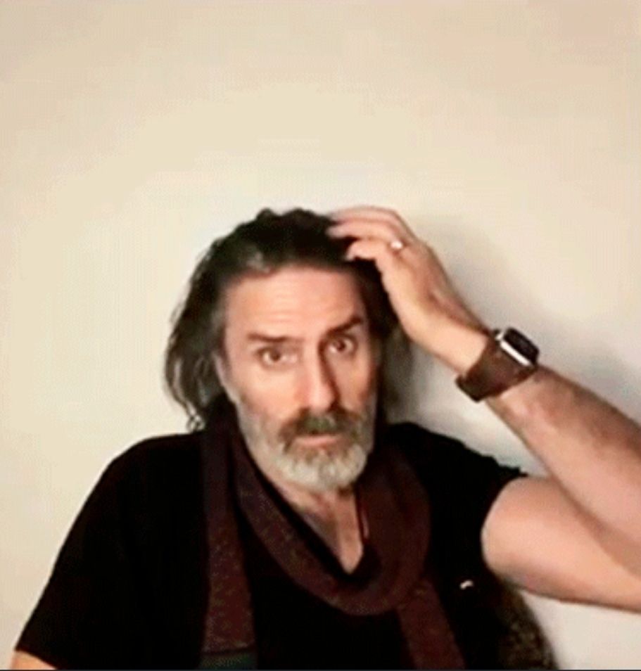 Con O'Neill scratching his hair looking at the camera 