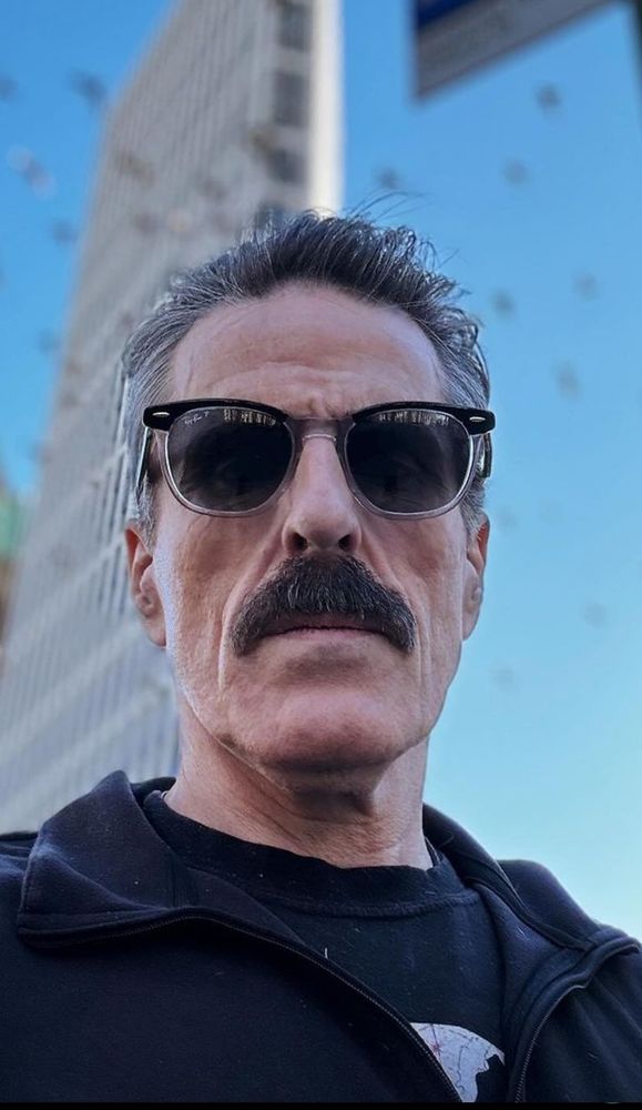 Con O'Neill selfie from below, he's wearing dark sunglasses. he has a dark moustache 