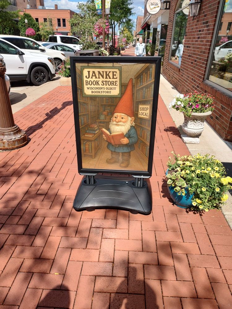 Sign of a garden gnome reading a book. The front door advertising for Janke Book Store