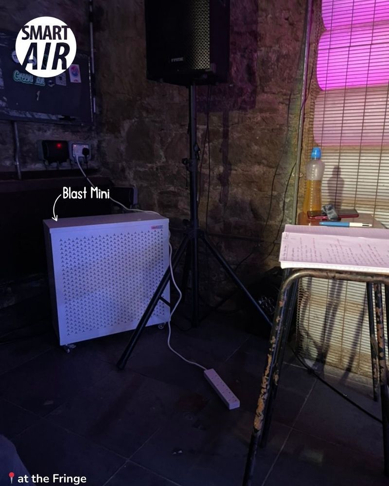 A Smart Air Blast Mini air purifier placed beside speakers and equipment in a small venue at the Fringe festival.