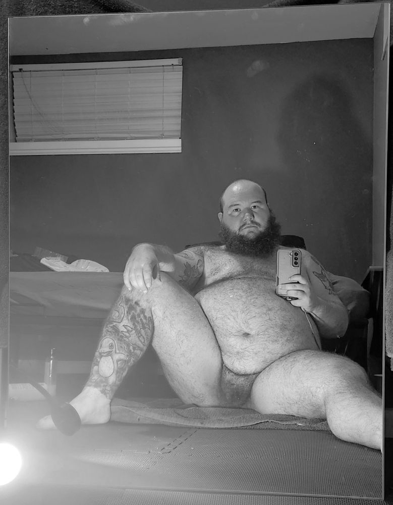 Black and white pictures of a hairy, chubby transgender man reflected in a mirror.