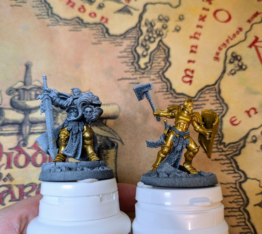 Two Stormcast Eternals miniatures painted with a greyish basecoat and some layers of gold.