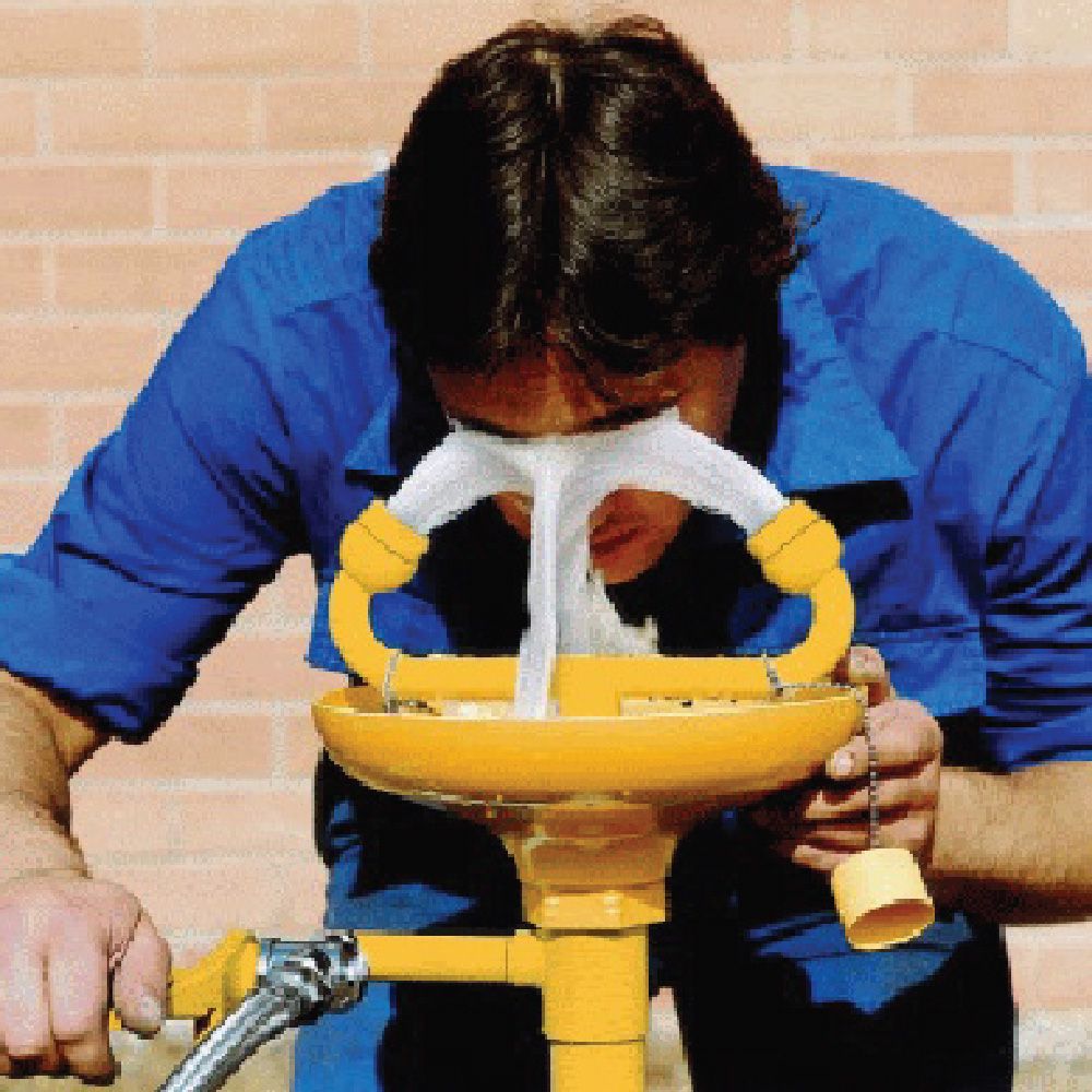 Un type en train de se nettoyer les yeux avec un laveur à yeux industriel 