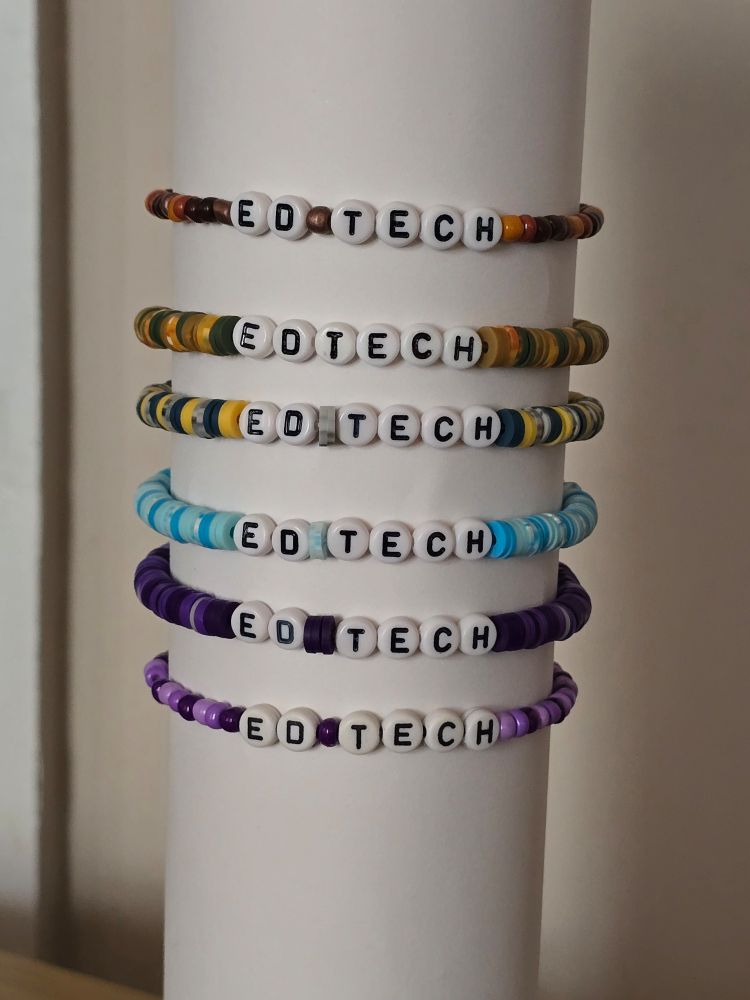 A stack of beaded bracelets in various colors with letter beads that say Ed Tech.