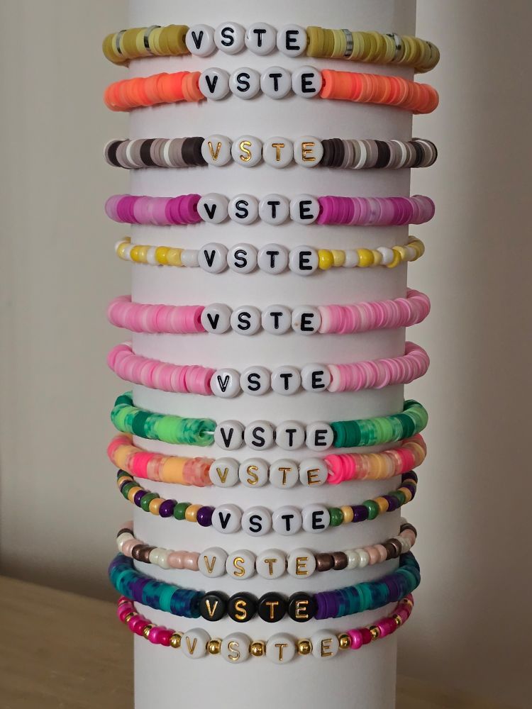 A stack of beaded bracelets in various colors with letter beads that say VSTE.