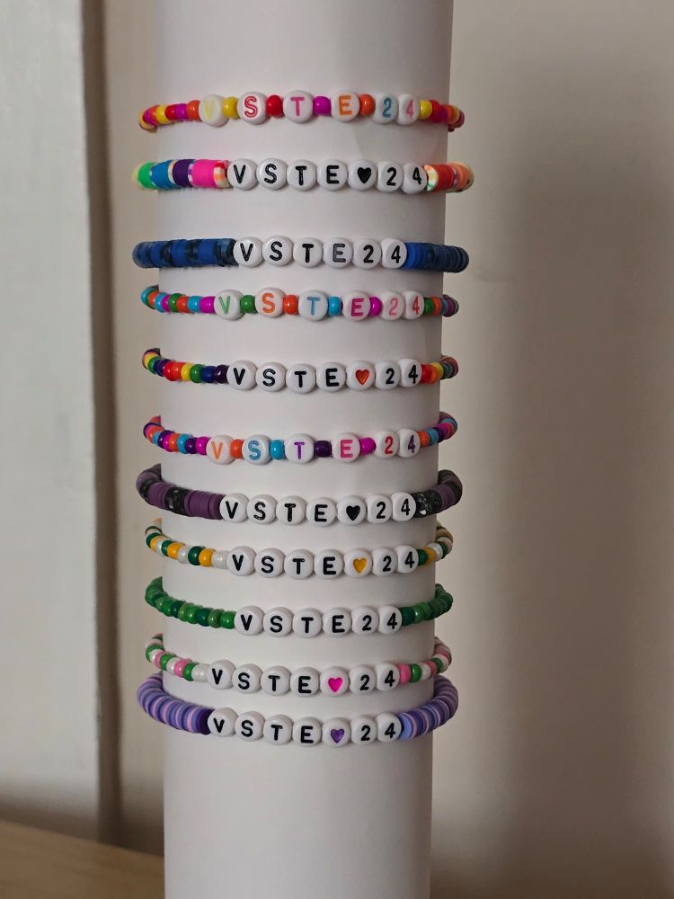 A stack of beaded bracelets with letter beads that say VSTE 24.