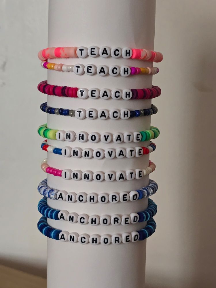 A stack of beaded bracelets with letter beads. Three say Anchored, three say Innovate, and four say Teach. 