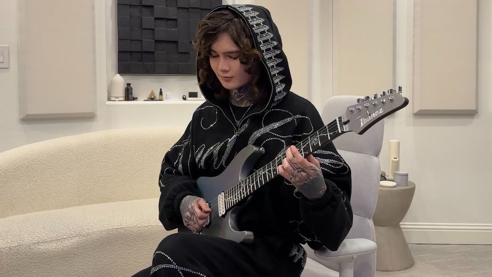 tim henson with a patterned black jacket and a fancy custom guitar being rich and stuff