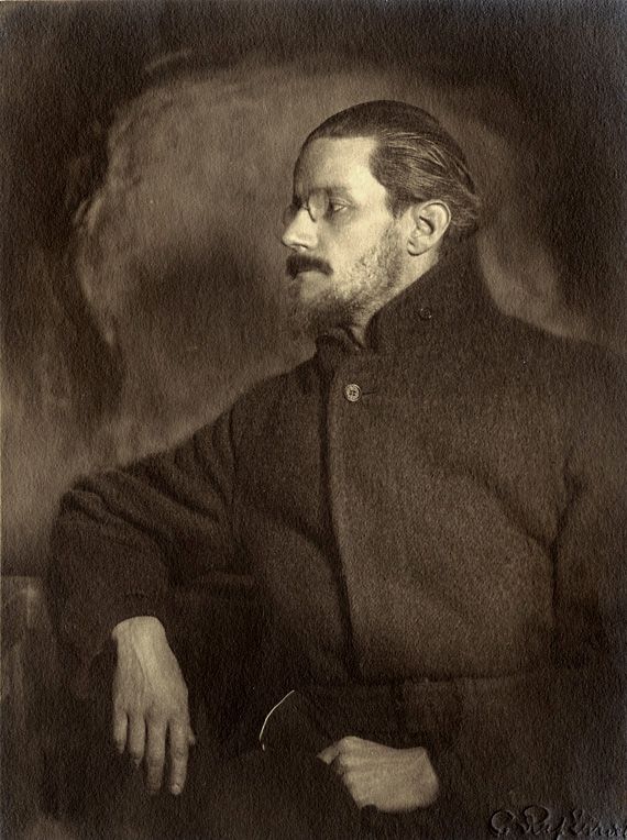 James Joyce at the age of 36. He is wearing a buttoned-up dark coat and glasses and his hair is swept back. He is looking sideways.