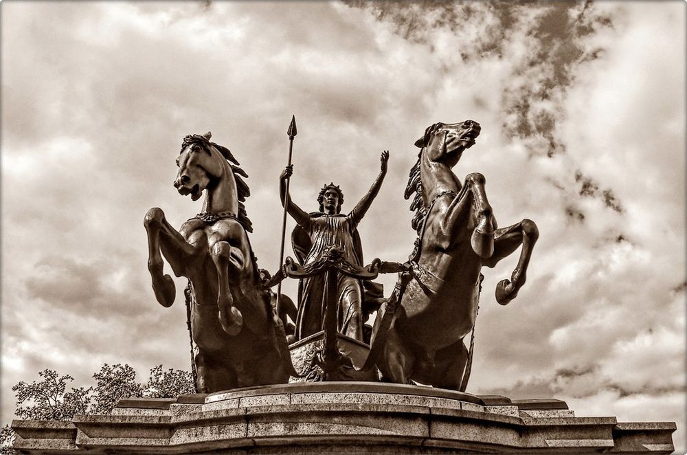 London statue depicting Boudicca grasping a spear and riding in a chariot pulled by two rearing horses.